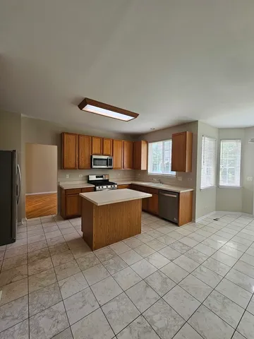 a large kitchen with a counter top space a sink and stainless steel appliances