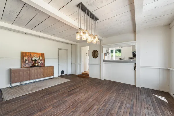 a kitchen with stainless steel appliances kitchen island granite countertop a refrigerator a stove a microwave oven with a dining table and chairs with wooden floor