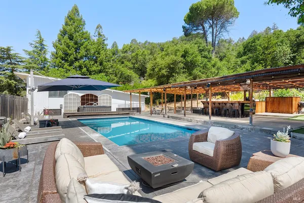 a view of a patio with couches table and chairs with potted plants and big yard