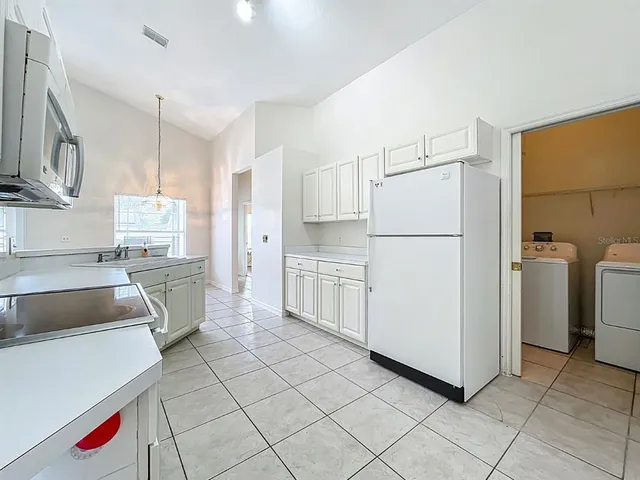 a kitchen with white cabinets and appliances