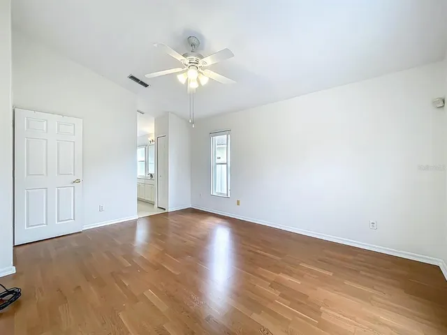 an empty room with wooden floor and windows