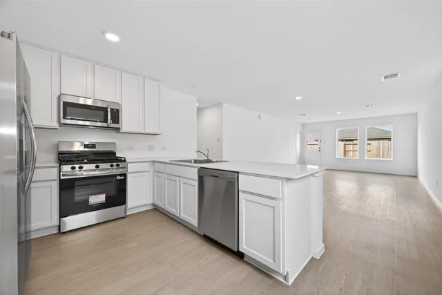 a kitchen with granite countertop white cabinets and stainless steel appliances