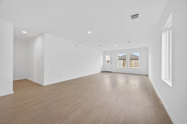 a view of an empty room with a window and wooden floor