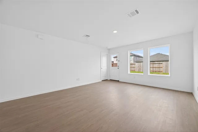an empty room with wooden floor and windows
