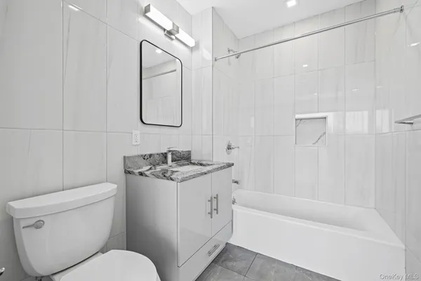 a view of an empty room with wooden floor and a bathroom