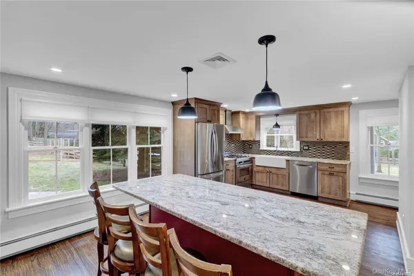 a kitchen with stainless steel appliances granite countertop a stove top oven a sink dishwasher a dining table and chairs with wooden floor