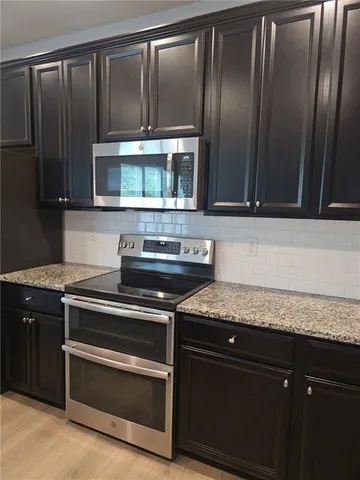 a kitchen with granite countertop wood cabinets and stainless steel appliances