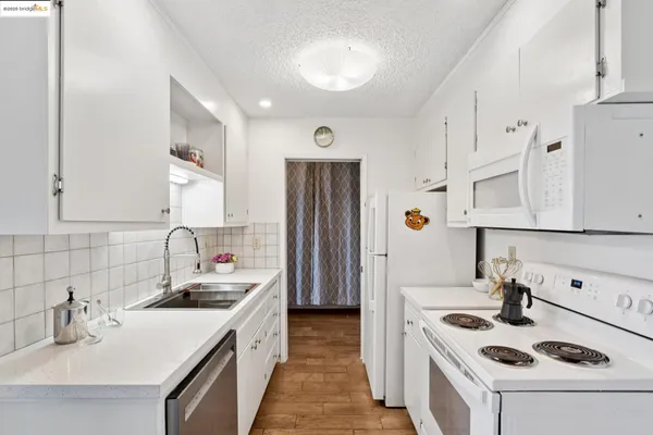 a kitchen with stainless steel appliances granite countertop a sink dishwasher and a refrigerator with wooden floor