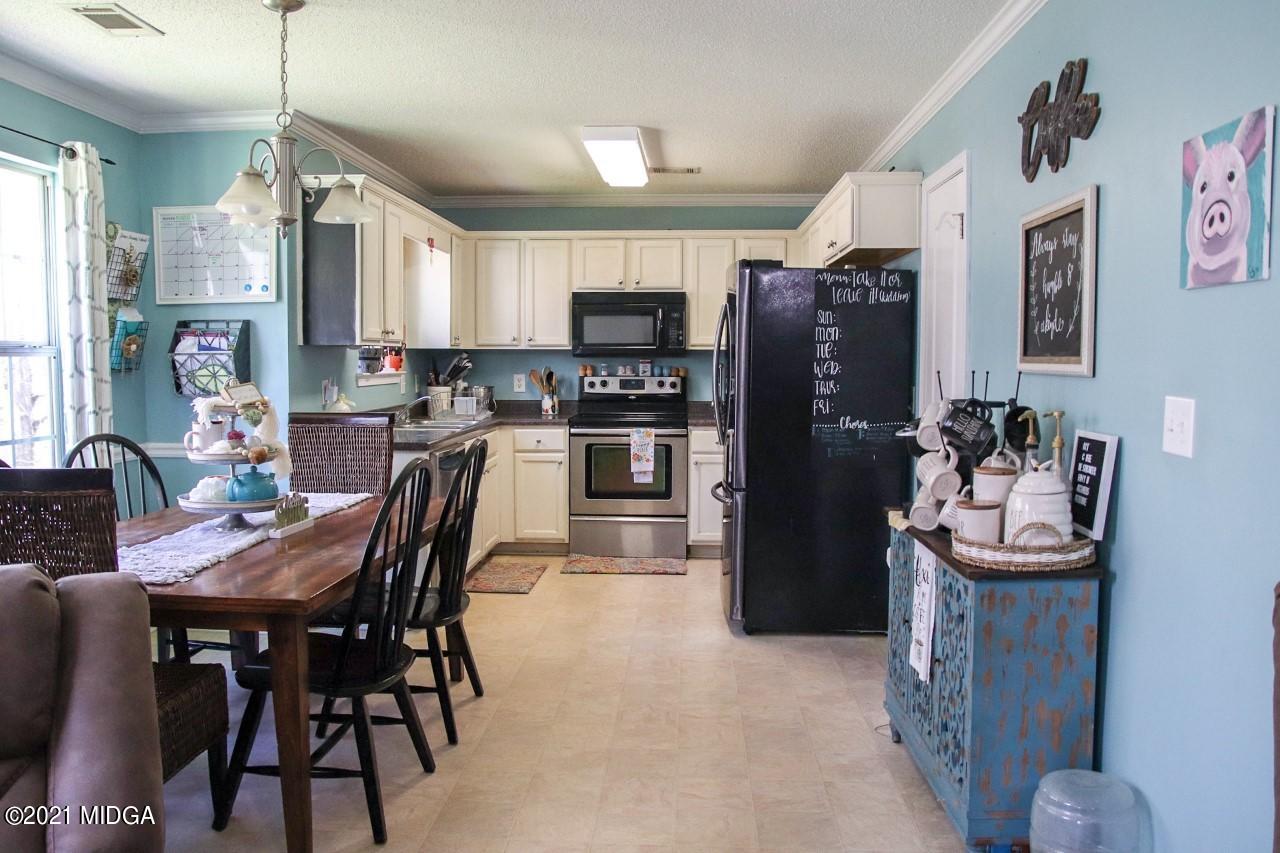 3369 Trotters Ridge Trail Gray, GA 31032 - Photo 2 of 13 a kitchen with stainless steel appliances granite countertop a dining table chairs refrigerator and sink