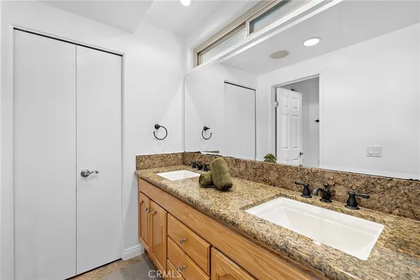 a bathroom with a granite countertop double vanity sink and mirror