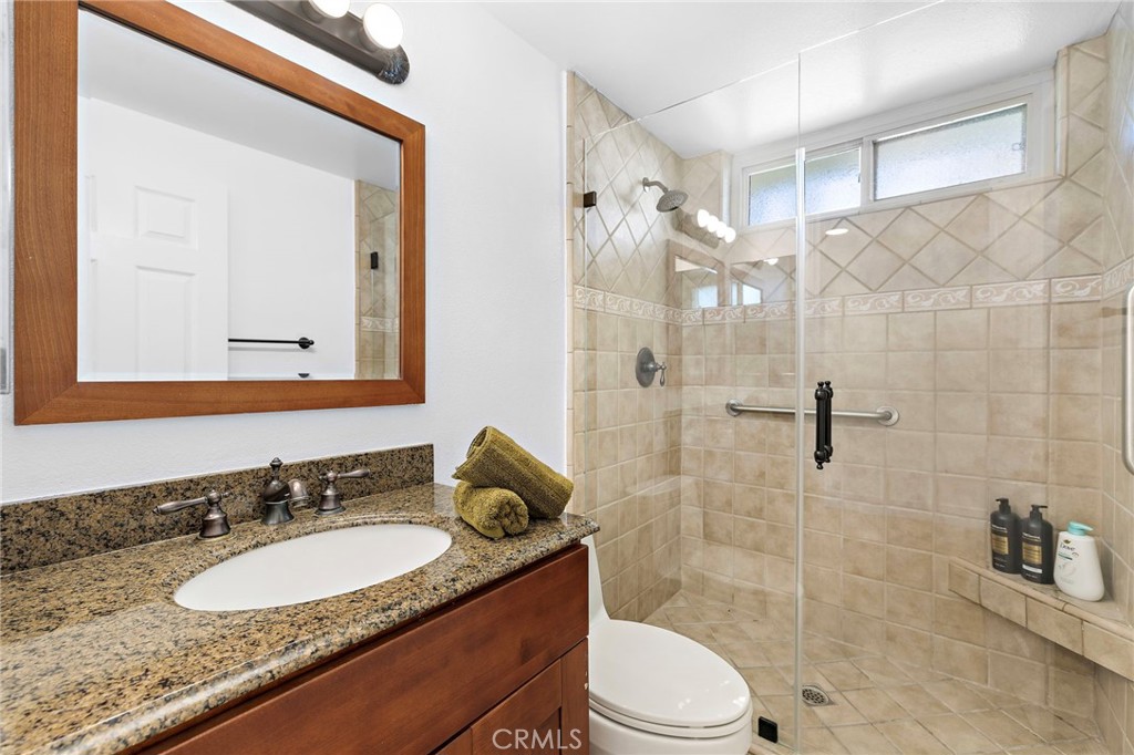 18 Navarre, Unit 133 Irvine, CA 92612 - Photo 18 of 32 a bathroom with a granite countertop sink toilet a mirror a vanity and shower
