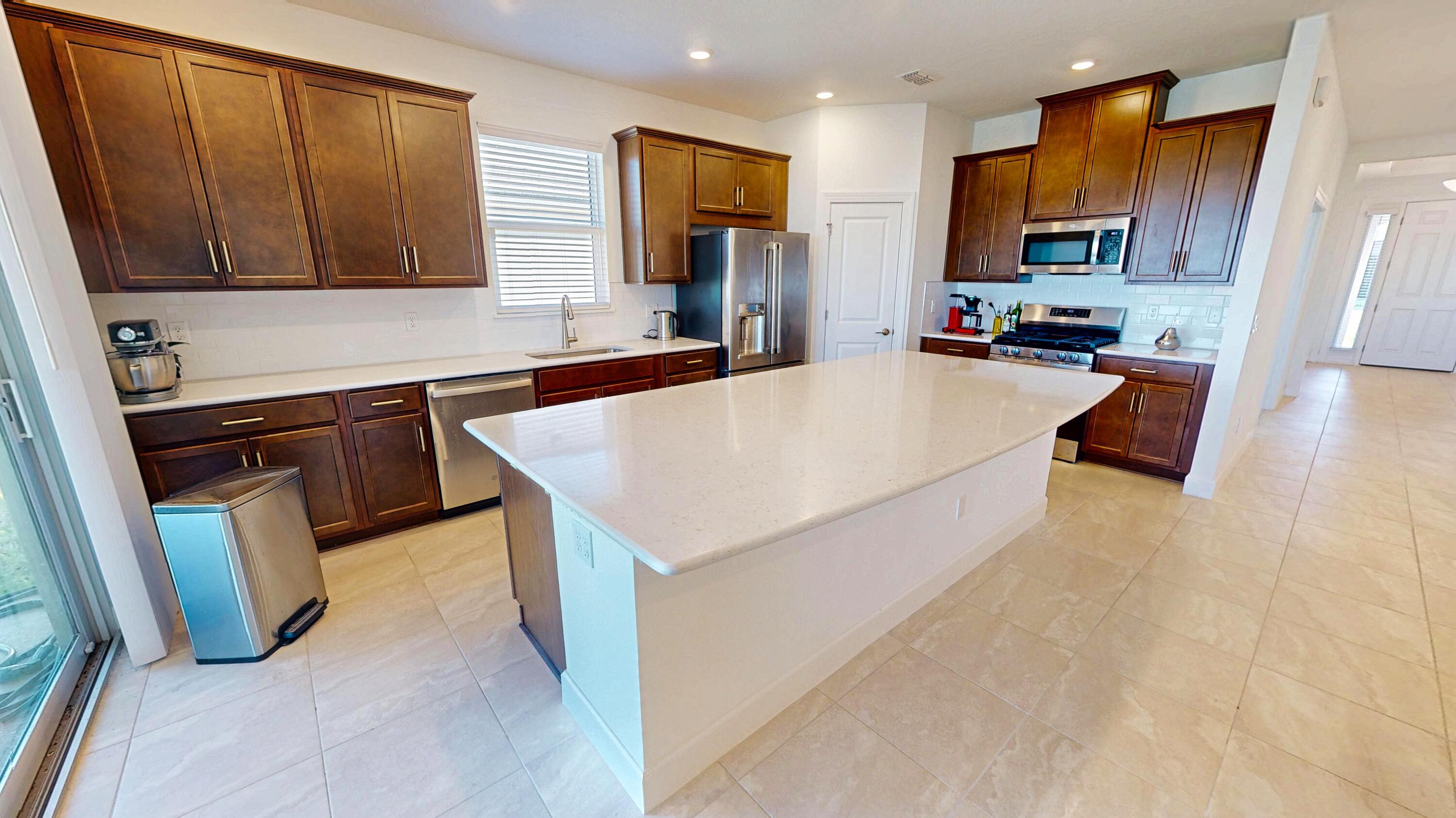 9876 Santini Road Port St. Lucie, FL 34987 - Photo 6 of 45 a kitchen with kitchen island granite countertop a stove top oven a sink a dining table and chairs