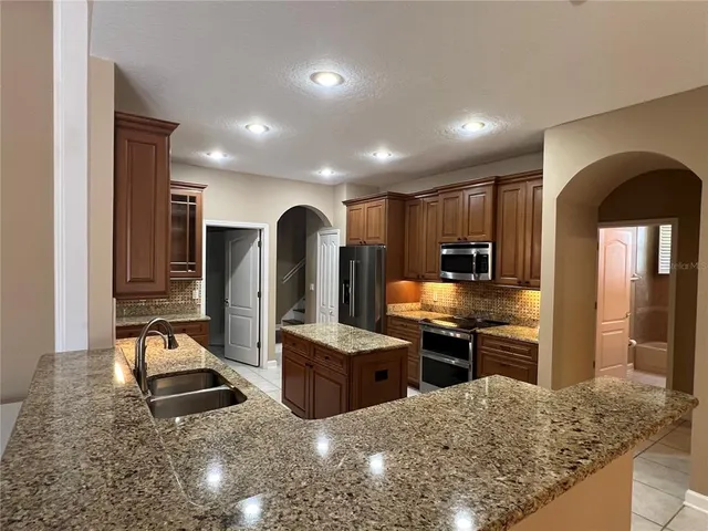 a kitchen with stainless steel appliances kitchen island granite countertop a refrigerator and stove