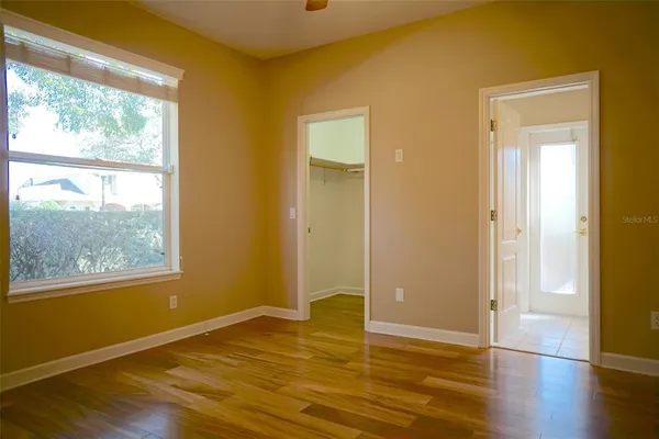 a view of an empty room with wooden floor and a window