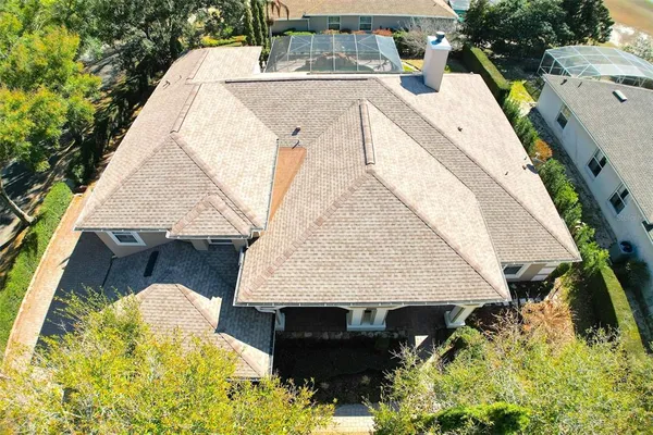 an aerial view of a house with swimming pool and large trees