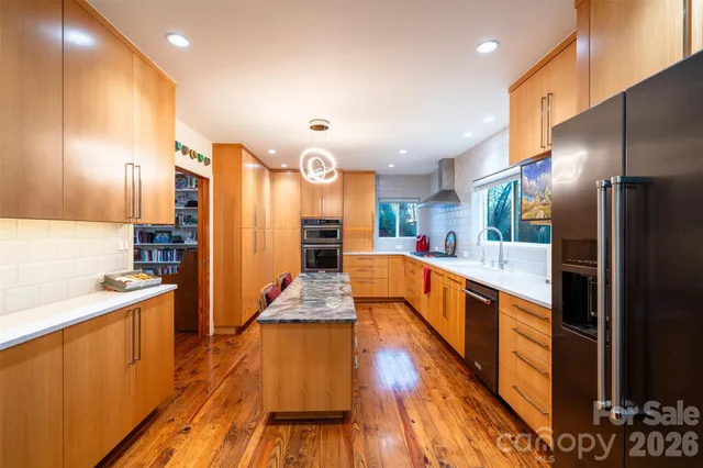 a large kitchen with stainless steel appliances kitchen island granite countertop a large kitchen island and a sink