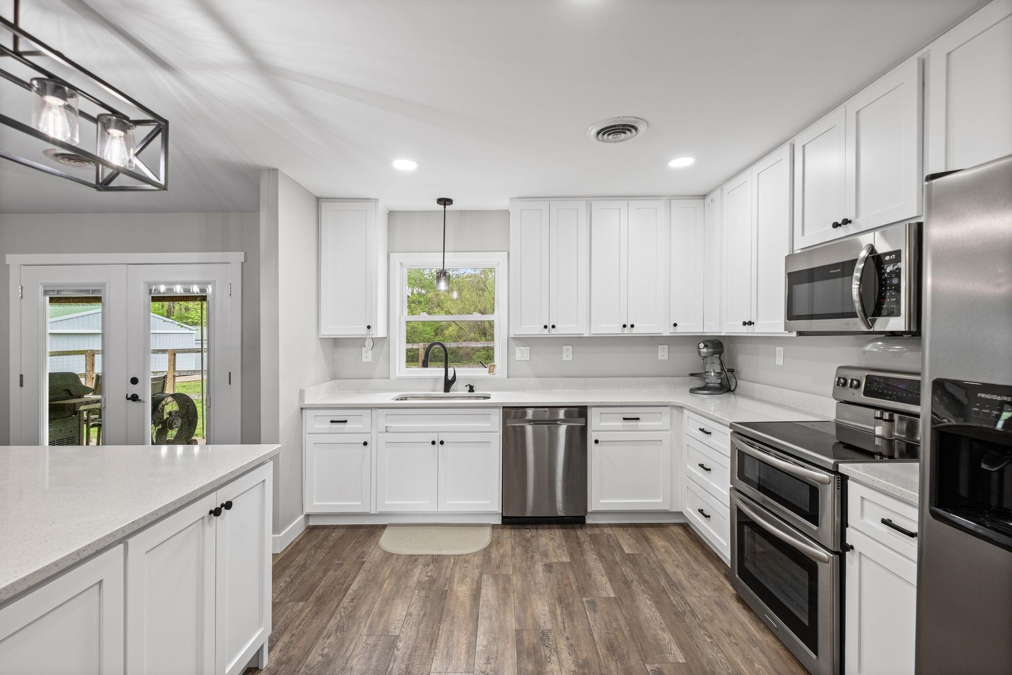 58 Hayes Road Munford, TN 38058 - Photo 12 of 40 Kitchen with white cabinets, stainless steel appliances, dark wood-type flooring, french doors, and light stone counters