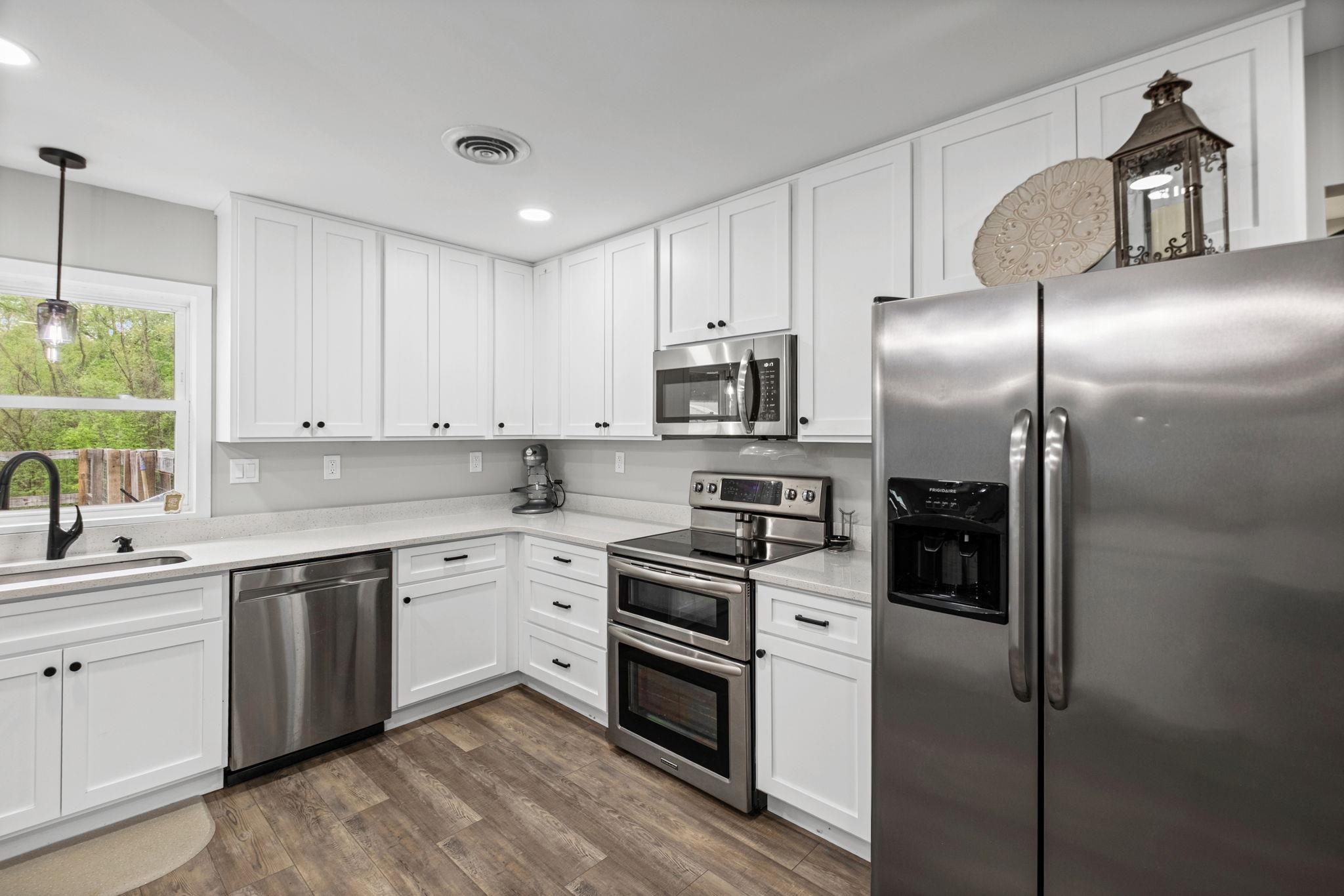 58 Hayes Road Munford, TN 38058 - Photo 13 of 40 Kitchen featuring stainless steel appliances, white cabinets, dark wood-style flooring, and light stone countertops