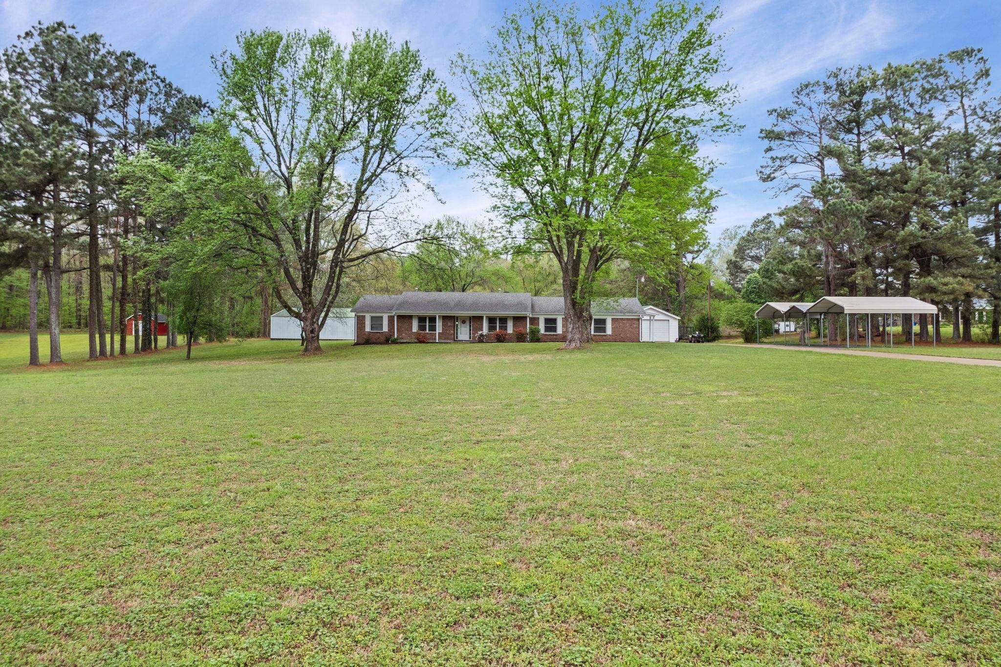 58 Hayes Road Munford, TN 38058 - Photo 3 of 40 View of grassy yard with an outbuilding, a detached carport, view of scattered trees, and covered porch