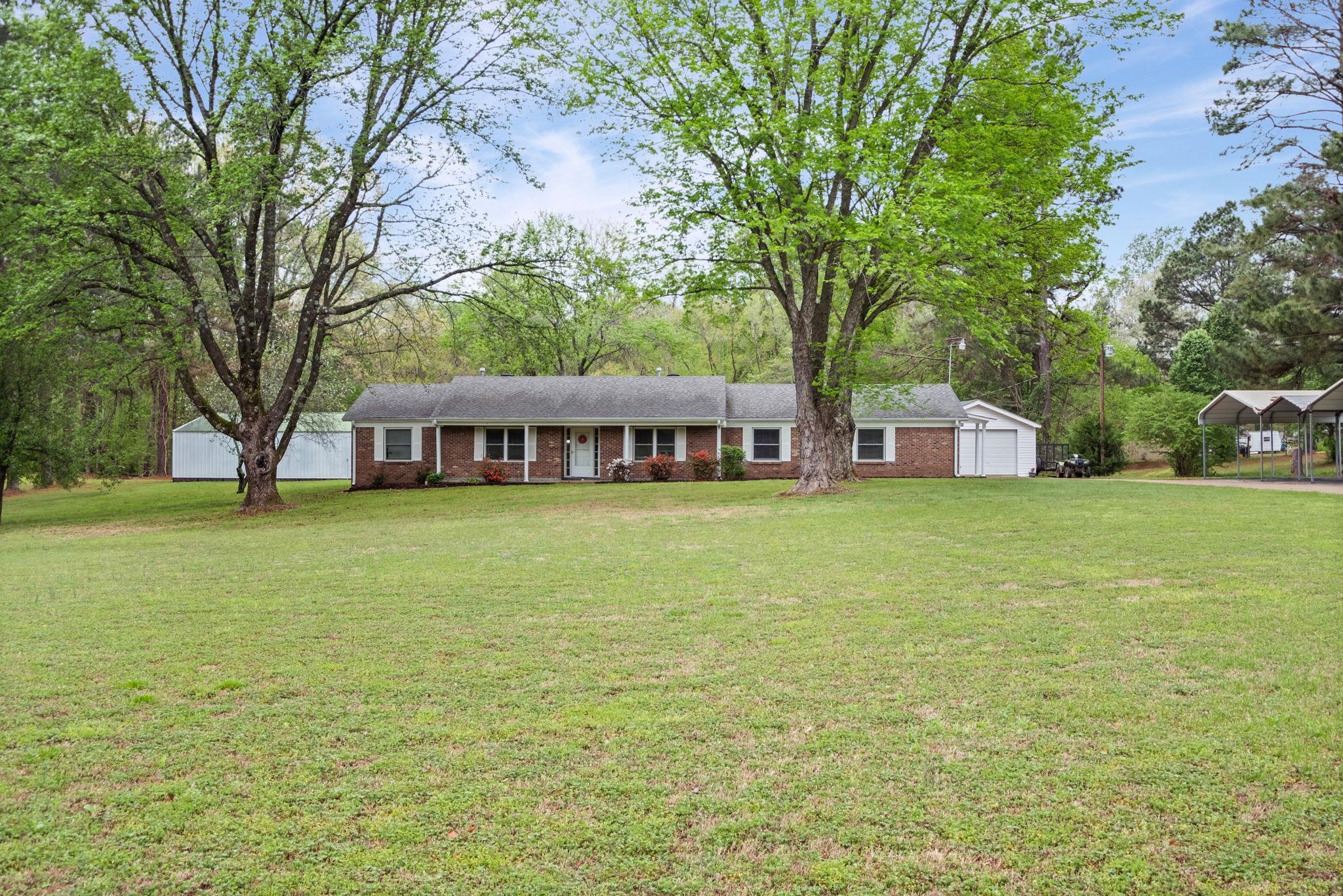 58 Hayes Road Munford, TN 38058 - Photo 5 of 40 Ranch-style house featuring a front yard, brick siding, an outdoor structure, and view of wooded area