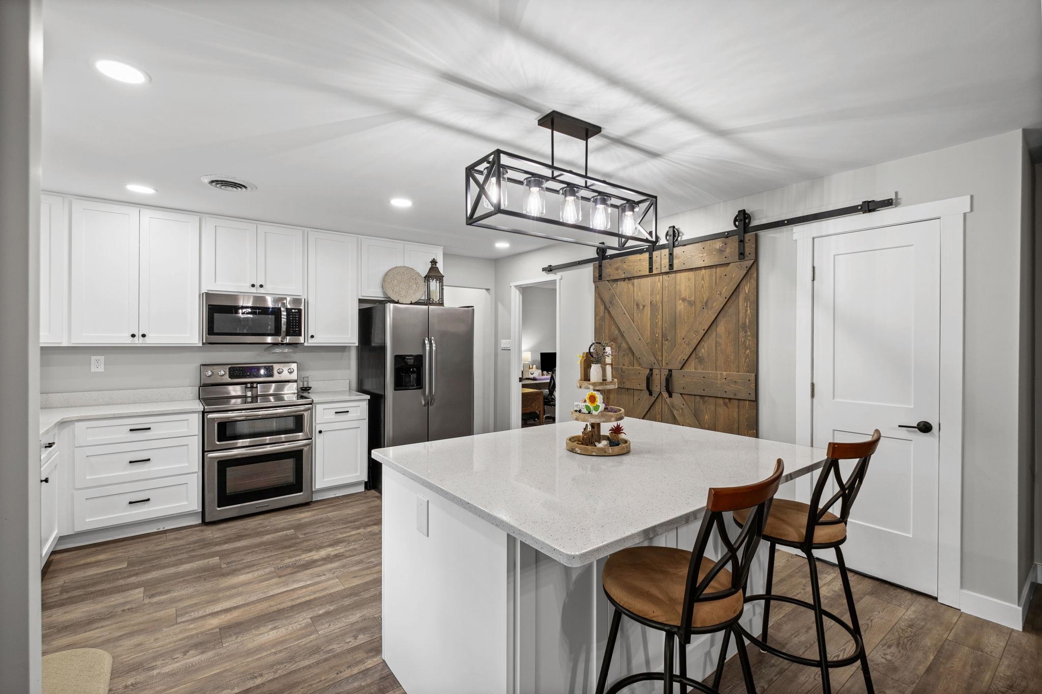 58 Hayes Road Munford, TN 38058 - Photo 8 of 40 Kitchen with stainless steel appliances, white cabinetry, a barn door, and a breakfast bar area