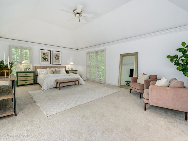 a spacious bedroom with a bed a couch and a flat tv screen next to a window