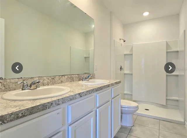 a bathroom with a granite countertop sink a toilet and shower