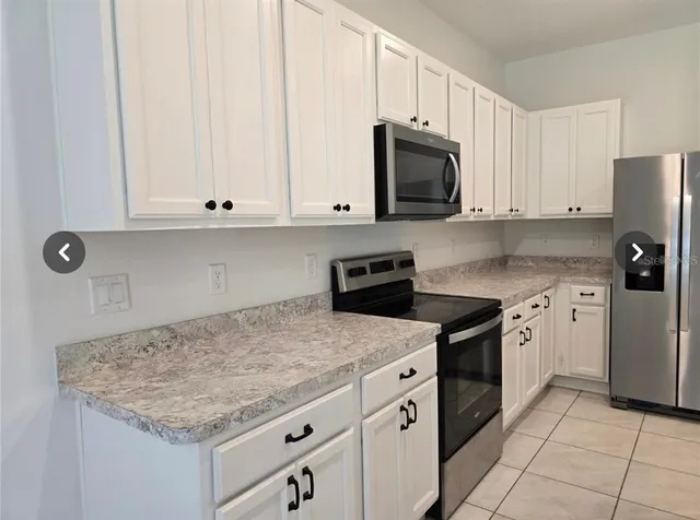 a kitchen with granite countertop white cabinets and stainless steel appliances