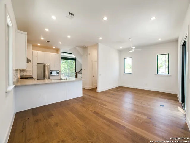 a view of an empty room with kitchen and window