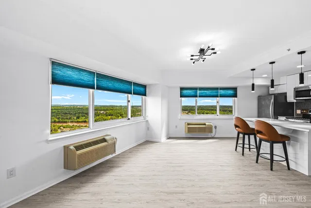a living room with furniture large windows and wooden floor
