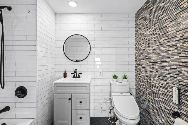 a bathroom with a toilet sink vanity and mirror