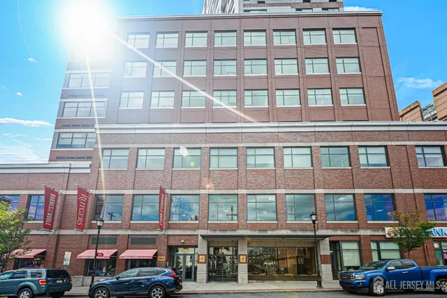 a front view of a building with a lot of cars and trees