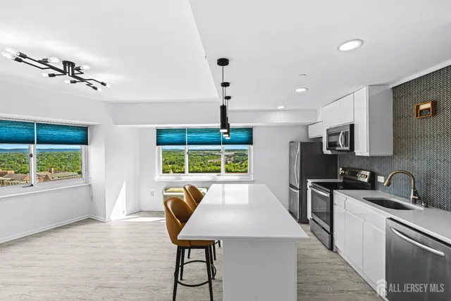 a kitchen with stainless steel appliances a table chairs in it and wooden floors