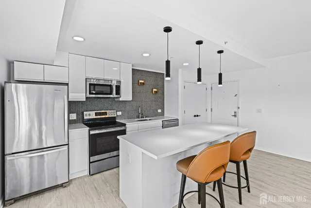 a kitchen with stainless steel appliances granite countertop a refrigerator a stove a microwave oven a sink a dining table and chairs