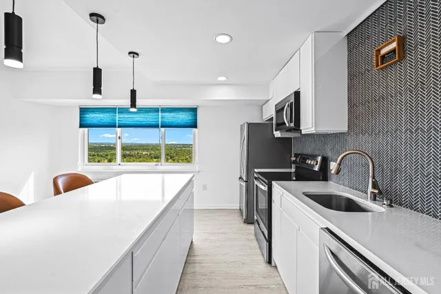 a kitchen with stainless steel appliances a sink a stove and a wooden floor