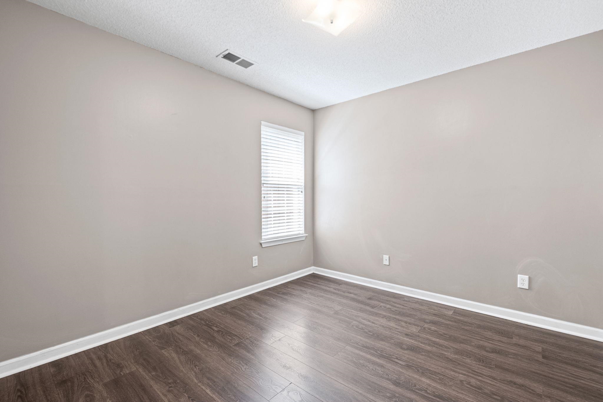 10018 Cameron Ridge Trail Memphis, TN 38016 - Photo 23 of 29 a view of an empty room with wooden floor and a window