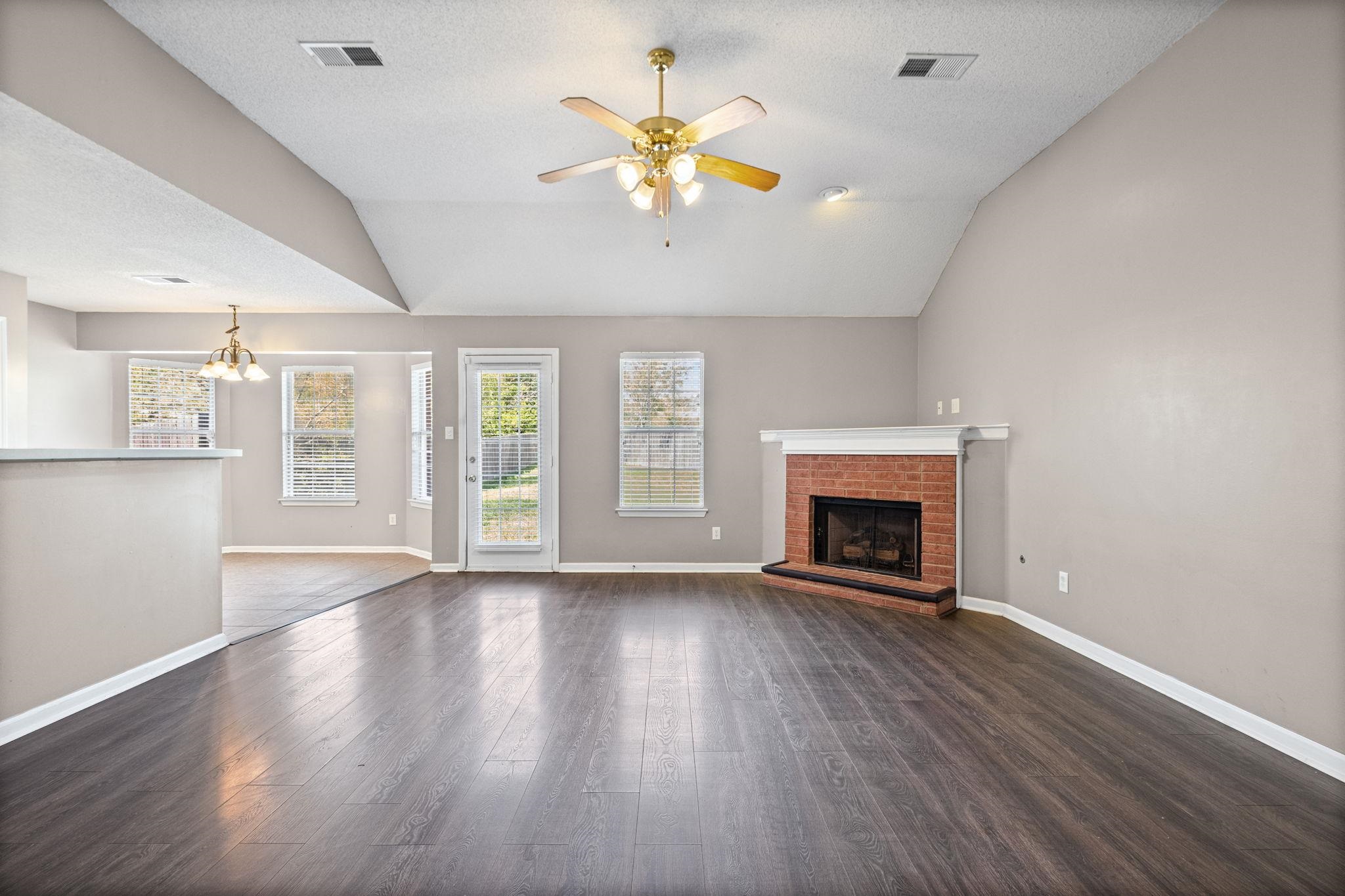 10018 Cameron Ridge Trail Memphis, TN 38016 - Photo 3 of 29 an empty room with windows a fireplace a ceiling fan and wooden floor