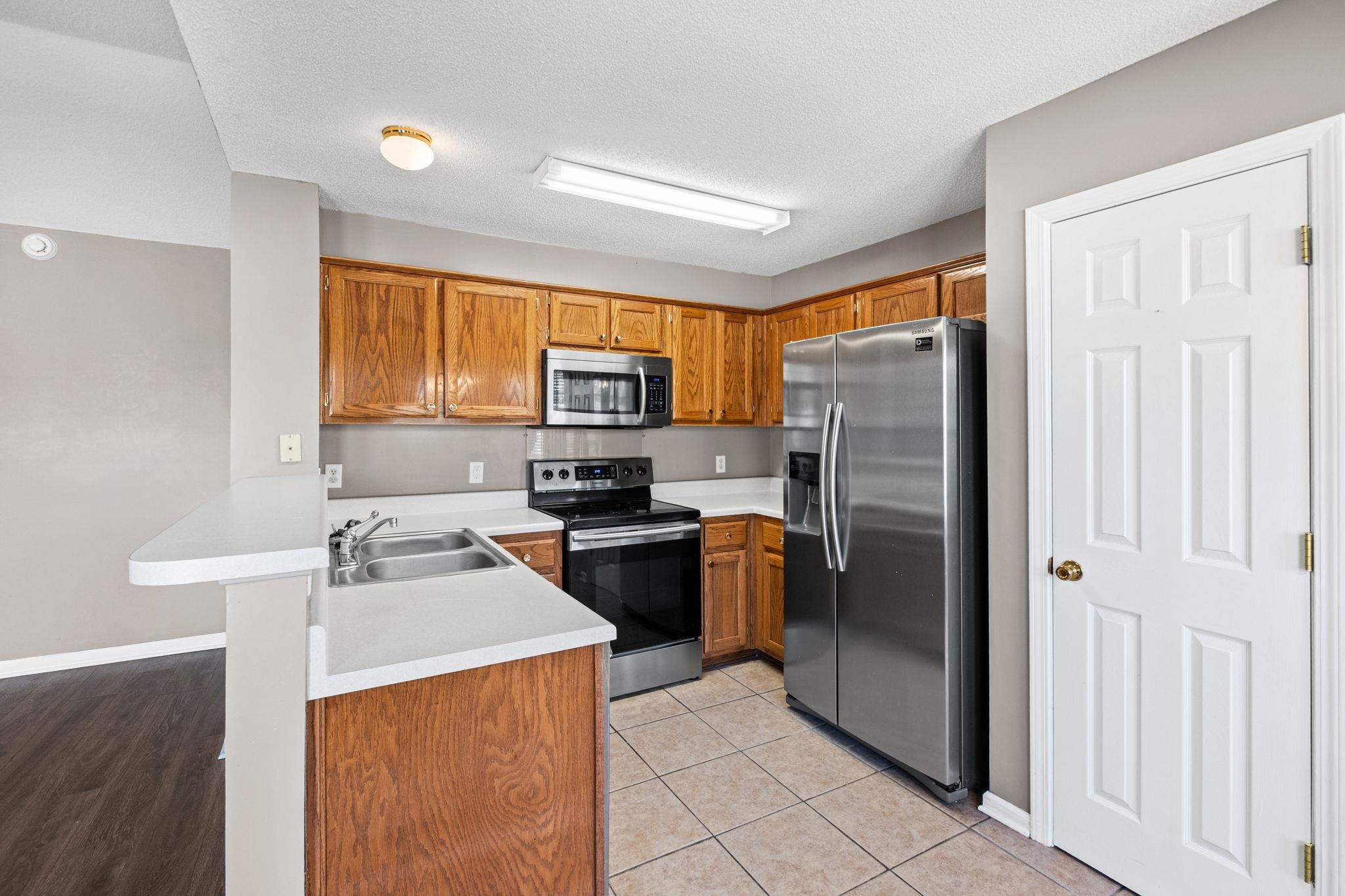 10018 Cameron Ridge Trail Memphis, TN 38016 - Photo 7 of 29 a kitchen with a refrigerator sink and wooden cabinets