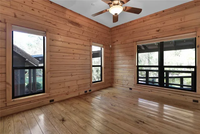 a view of an empty room with a window and wooden floor