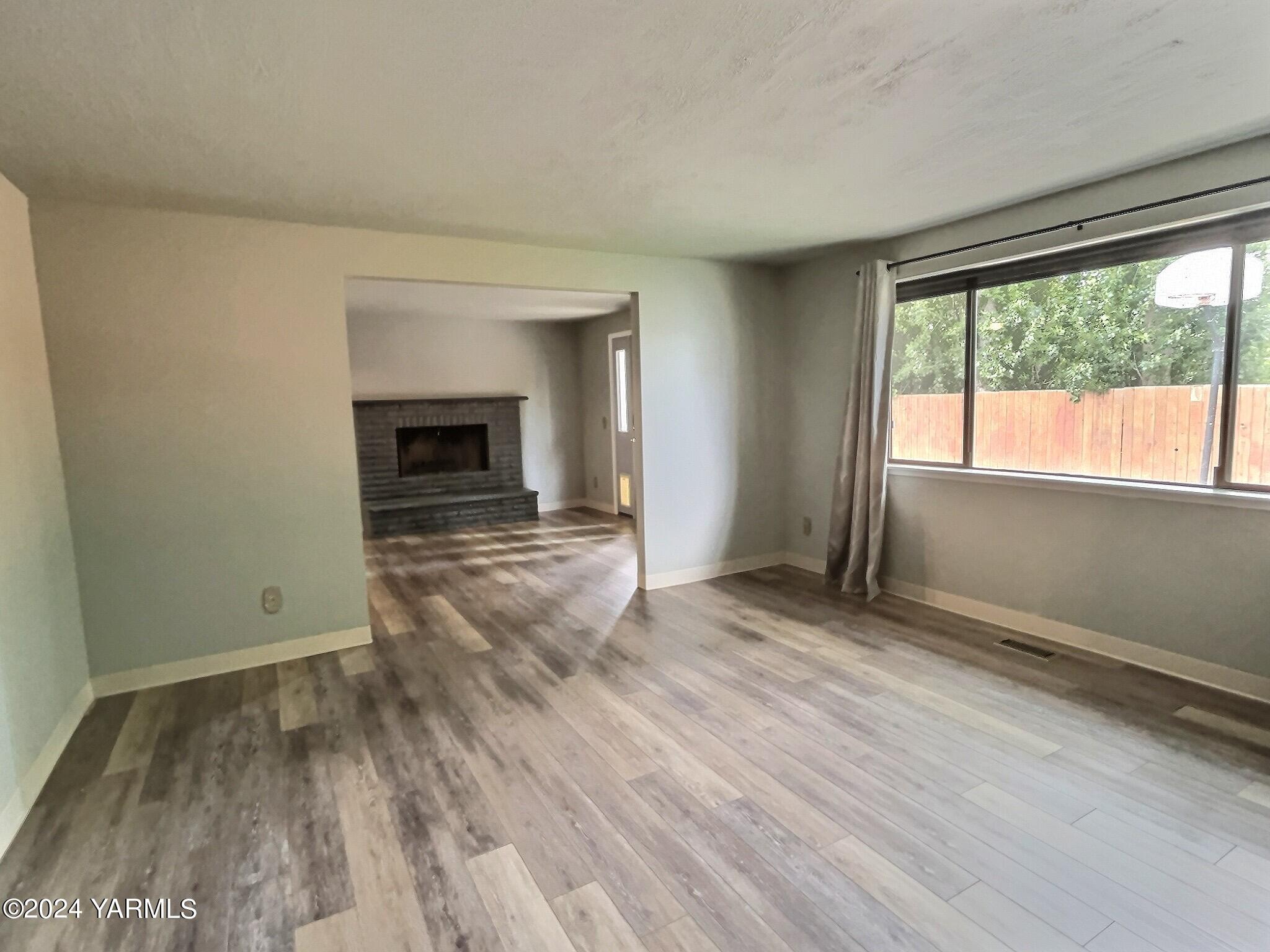 408 Wyant Way Grandview, WA 98930 - Photo 22 of 46 an empty room with wooden floor fireplace and windows