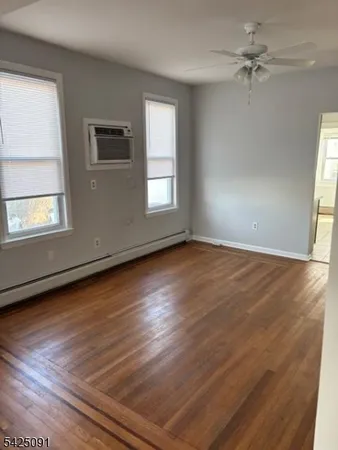 an empty room with wooden floor chandelier fan and windows