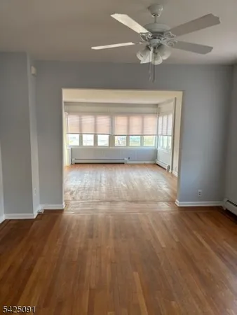a view of an empty room with a window and wooden floor