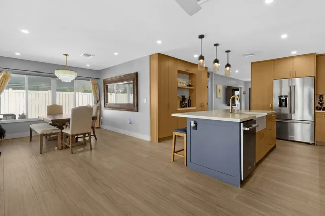 a kitchen with stainless steel appliances kitchen island granite countertop a table chairs and a refrigerator