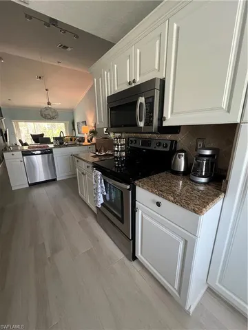 a kitchen with stainless steel appliances granite countertop a stove a sink and a microwave