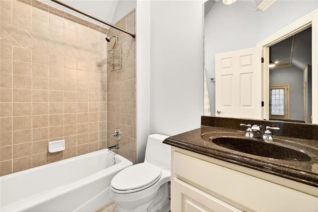 2910 Creek Tree Lane Cumming, GA 30041 - Photo 56 of 75 a bathroom with a granite countertop sink a toilet a mirror and bathtub