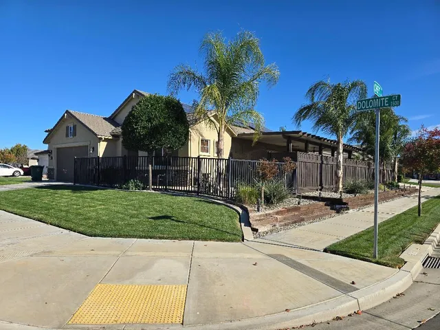a view of a house with a yard and table and chair under palm trees