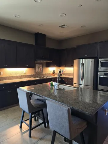 a kitchen with stainless steel appliances granite countertop a table chairs in it and granite countertops