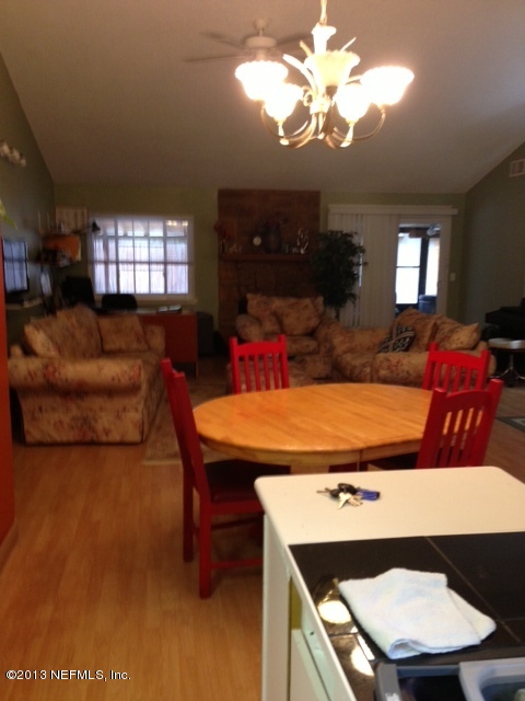 2441 Wattle Tree Road East Jacksonville, FL 32246 - Photo 6 of 13 a living room with furniture a chandelier a large window and a flat screen tv