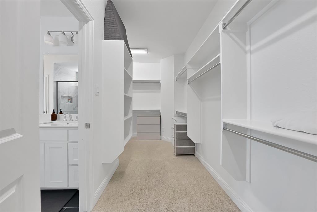 5012 Triadic Lane Prosper, TX 75078 - Photo 20 of 38 Walk-in closet with extensive built-in shelving, hanging rods, central storage island with drawers, and neutral carpeting