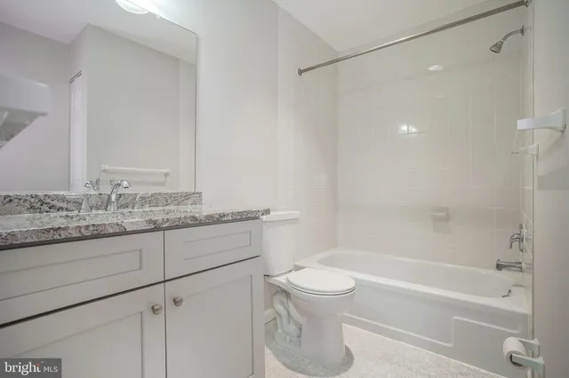 a bathroom with a granite countertop sink a toilet and shower